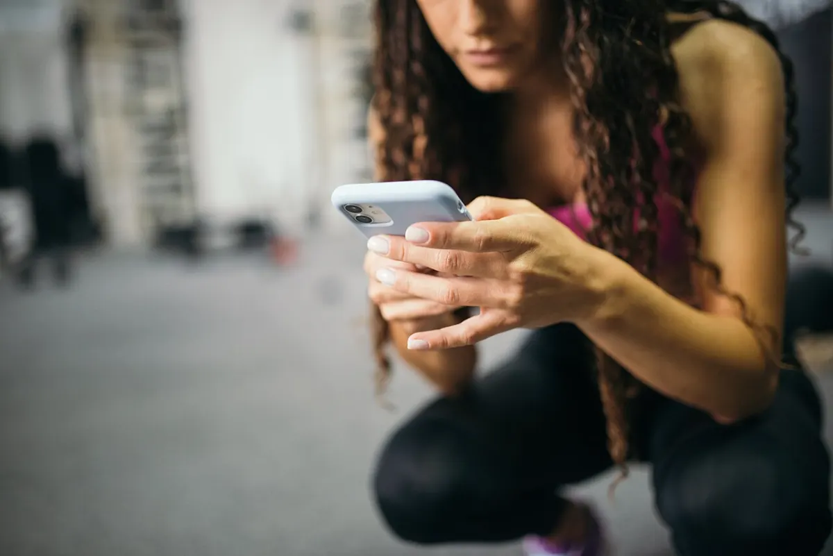 App Usage Tracker App - Young woman using a smartphone in the gym