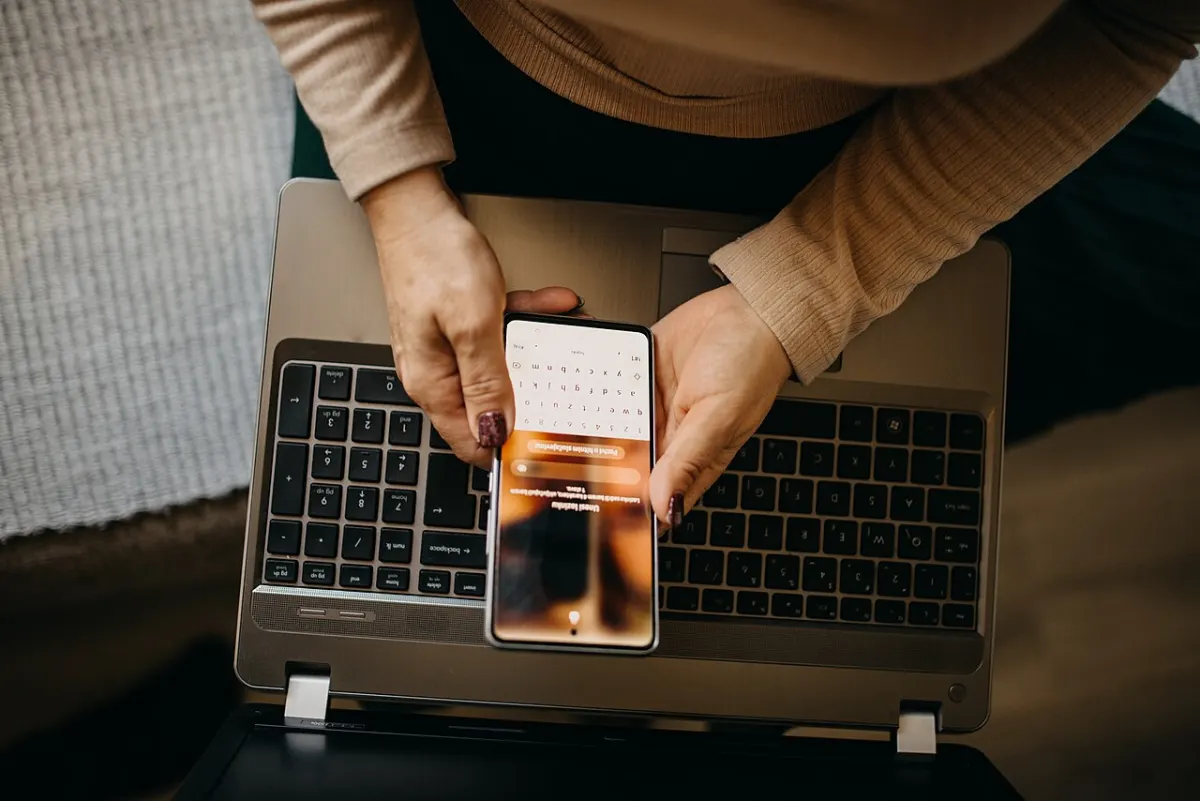 App Usage Tracker App - Middle-aged woman using a smartphone with laptop