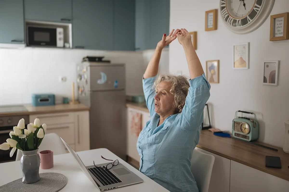 Asset Tracking Software - Woman stretches at home office desk while working on laptop