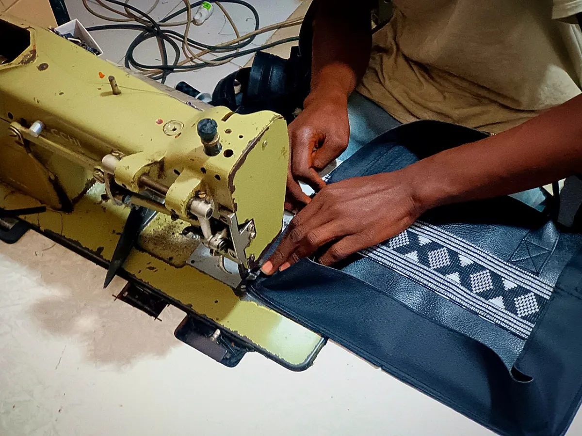 Boutique Management System - African tailor sewing a leather bag