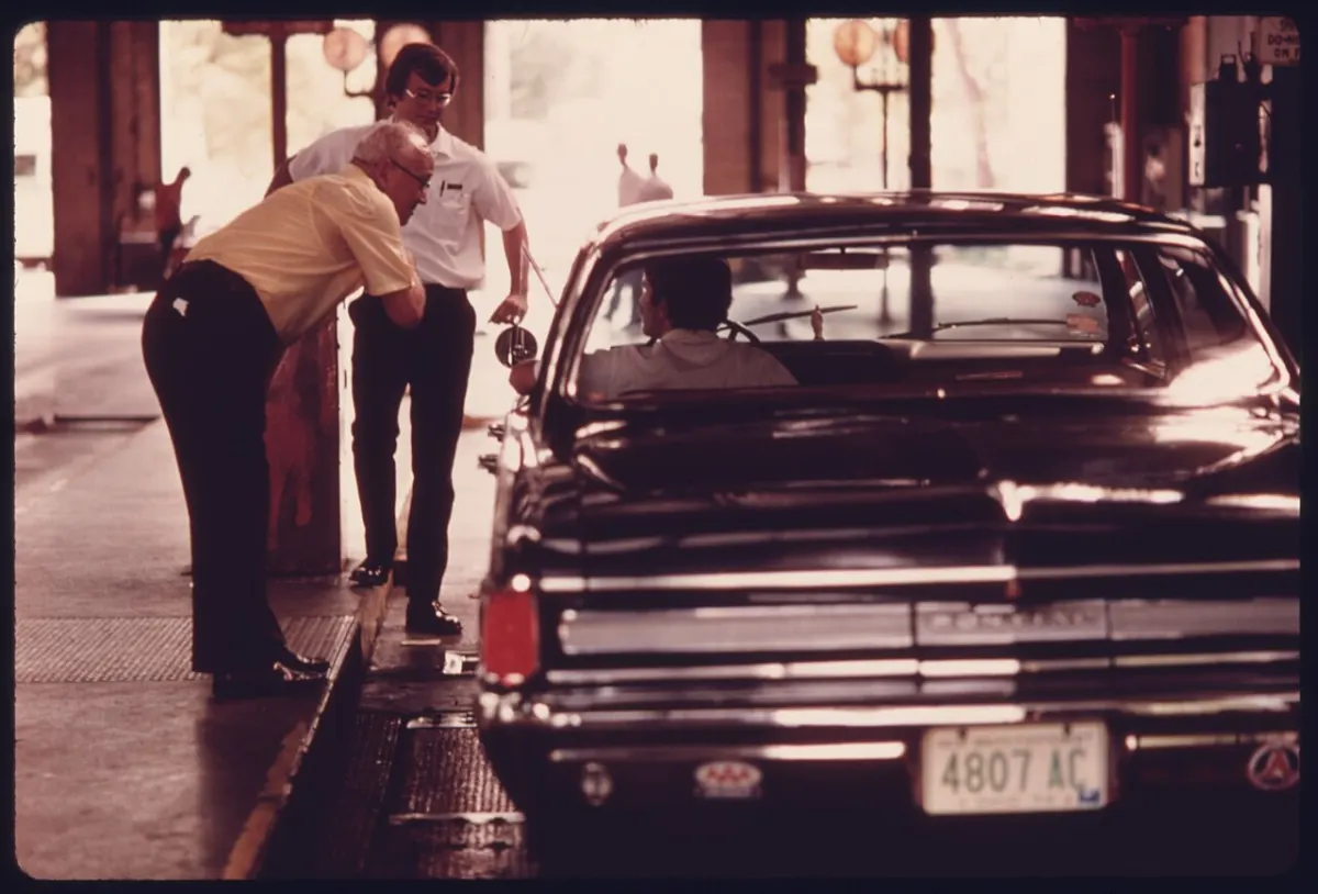 Driving License Management System - MOTORIST LEANS OVER TO TALK TO A CITY EMPLOYEE WHO IS DRIVING HIS CAR THROUGH THE TEST LAN