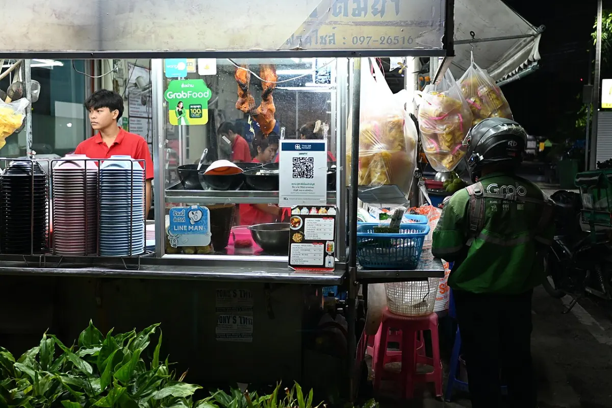 Food Delivery Website - DFC 1639 A nighttime street food stall lit up as a vendor prepares orders while a delivery