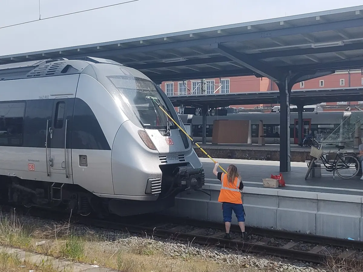 Home Service Booking App - Worker cleaning train windshield at Dessau Hbf
