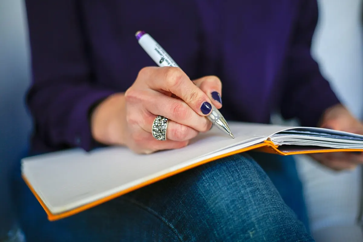Online Notepad - Woman writing on a notebook with a pen
