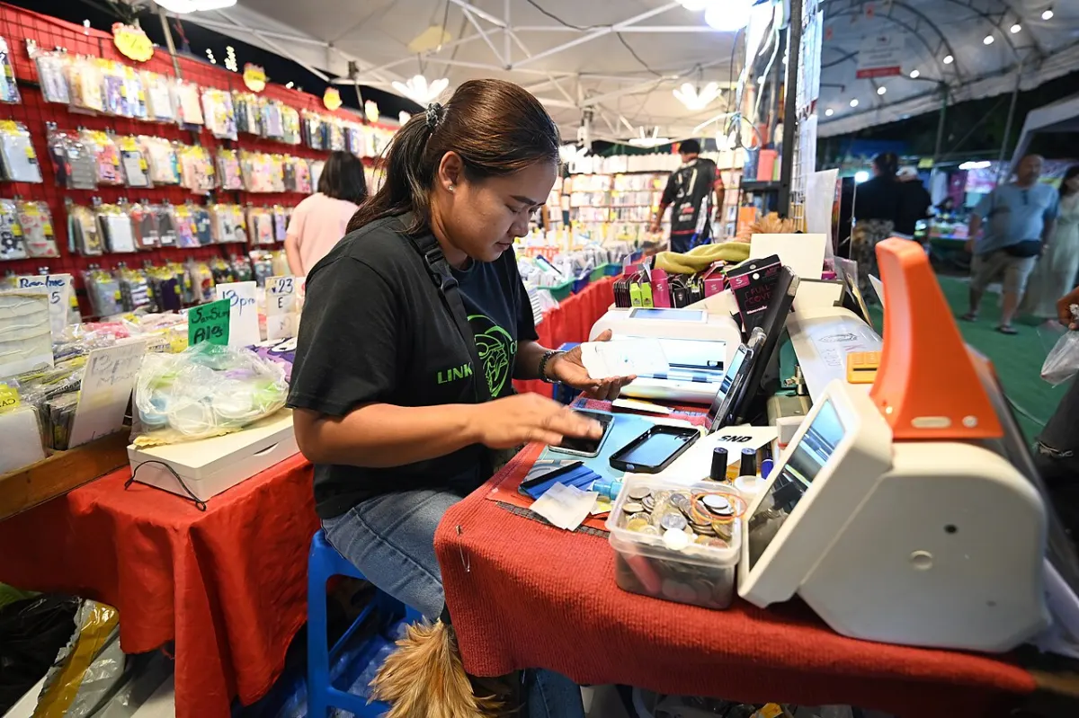 Real-Time Chat Application - A market vendor sits at a cluttered stall using a smartphone and point-of-sale tools to pr