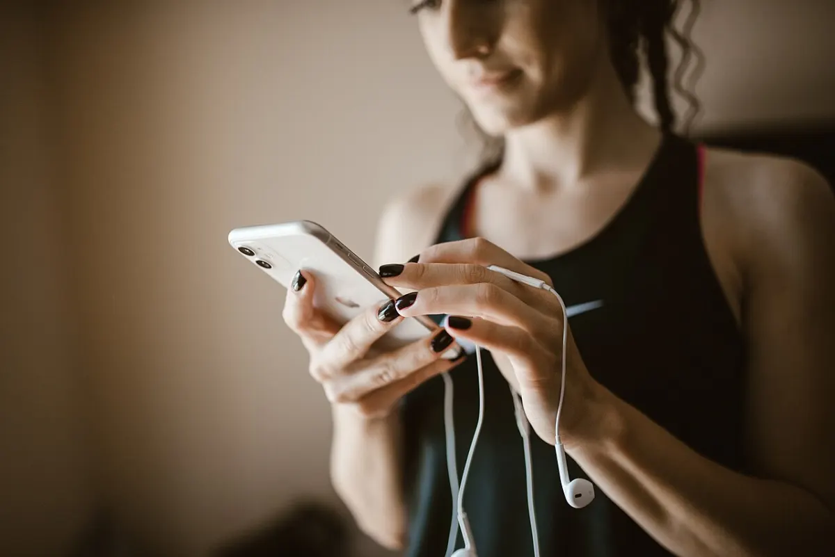 Ringtone Maker App - Woman using smartphone while listening to music in a fitness setting during the day
