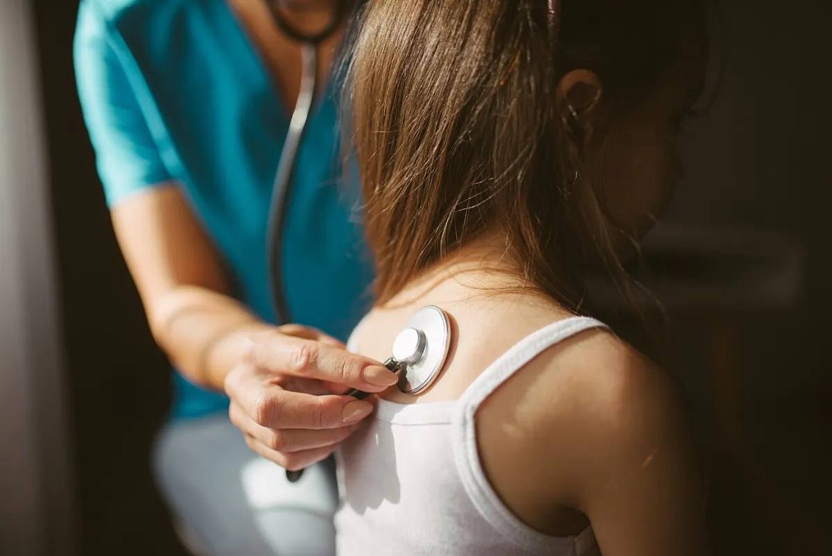 Symptom Checker App - Female doctor listens to the patient using a stethoscope closeup