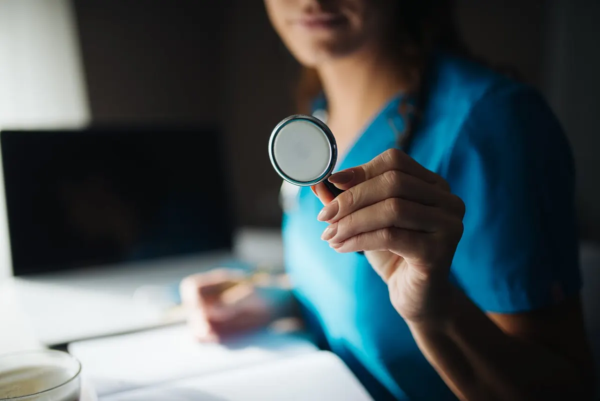 Symptom Checker App - Young female doctor showing stethoscope closeup